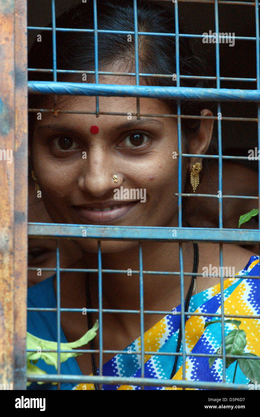 (Dpa-Datei) - das Bild zeigt eine junge Frau auf der Suche durch die vergitterten Fenster des AIDS-Informationszentrums in einem abgelegenen Dorf in der Nähe von Chandrapur, Indien, 2. Juli 2006. Foto: Wolfgang Langenstrassen Stockfoto