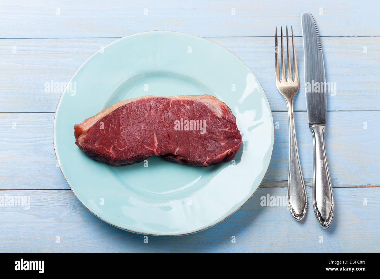 rohes Steak auf einem blauen Teller Stockfoto