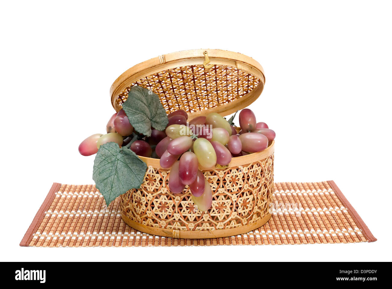 Bast Korb mit einem Trauben wird auf weißem Hintergrund fotografiert. Stockfoto