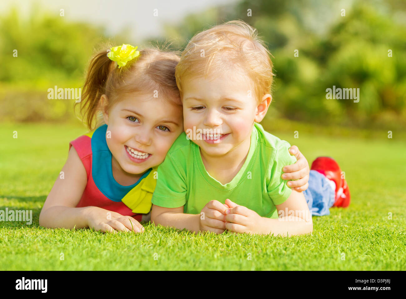 Bild von zwei glückliche Kinder, die Spaß im Park, Bruder und Schwester liegend auf dem grünen Rasen, beste Freunde, spielen im freien Stockfoto