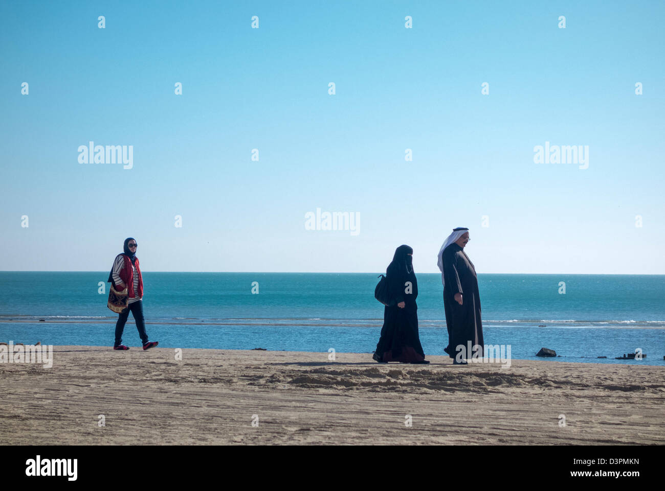 Arabische Familie, die zu Fuß am Strand, neben Mövenpick Hotel & Resort, Al Bida'a, Kuwait Stockfoto