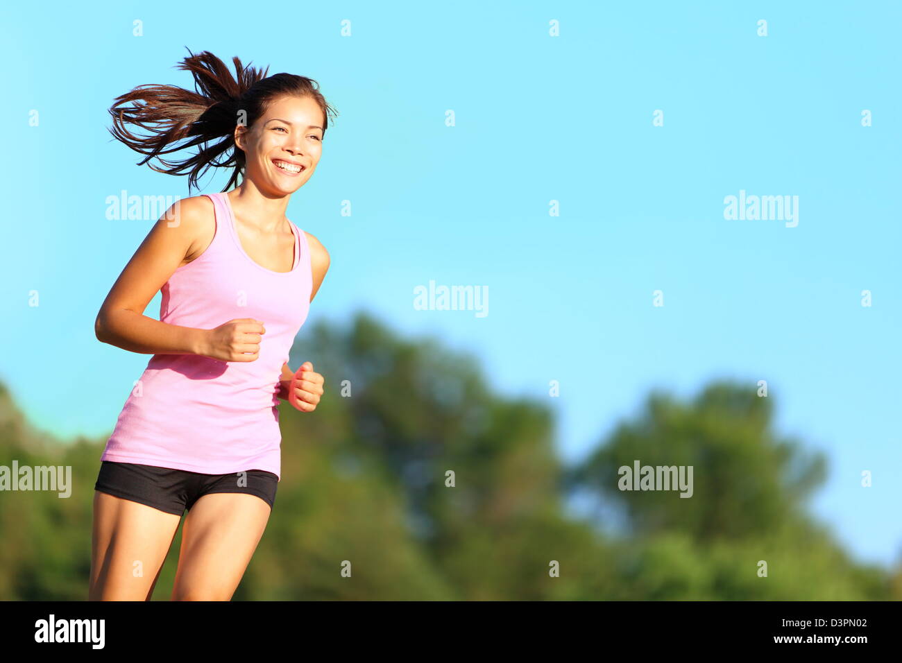 Lächelnde junge gemischte Rennen asiatische Chinesisch / Caucasian weibliche Läufer Joggen im Stadtpark am schönen Sommertag Stockfoto