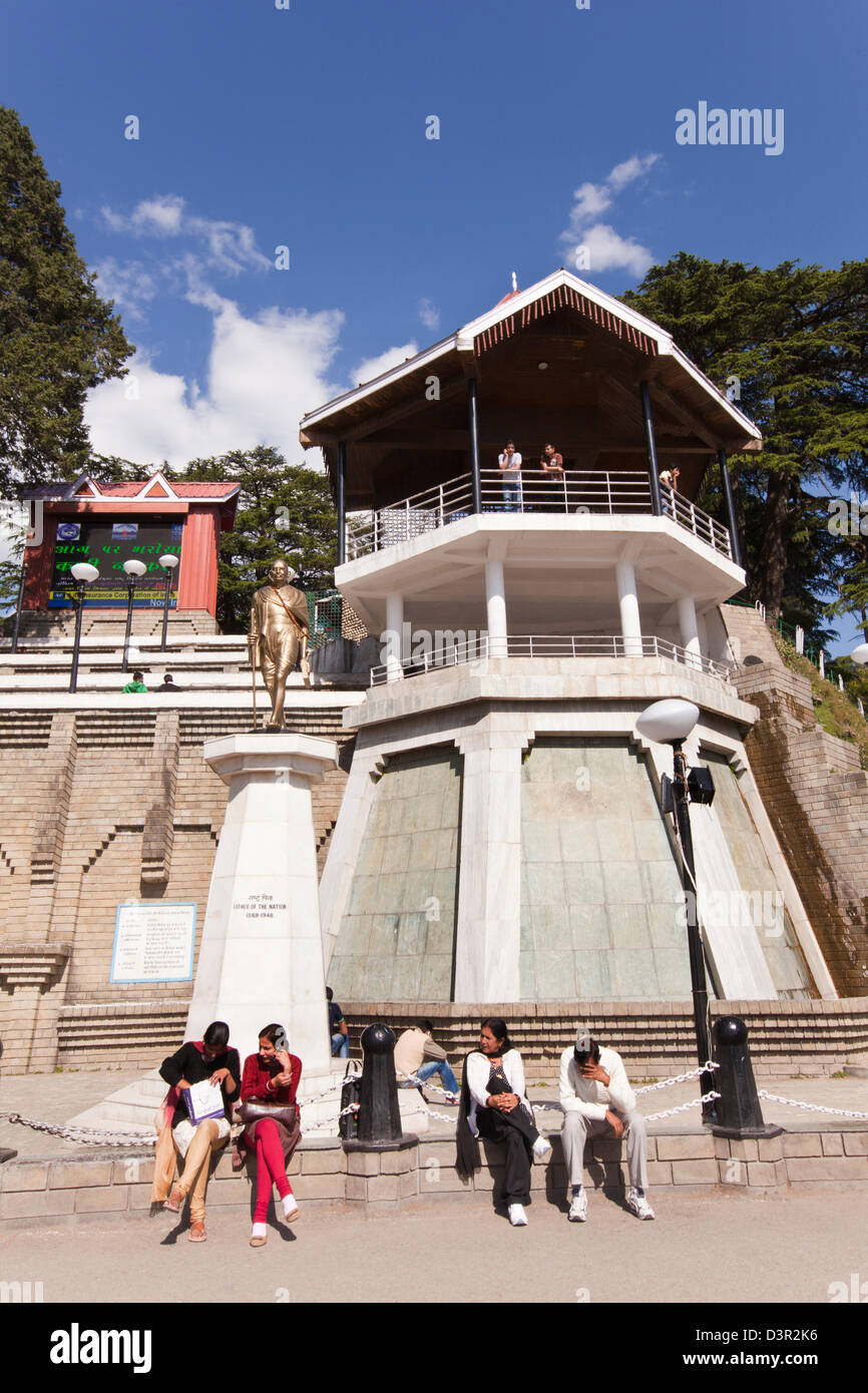 Touristen sitzen in der Nähe eine Statue von Mahatma Gandhi am Stadtplatz, Shimla, Himachal Pradesh, Indien Stockfoto