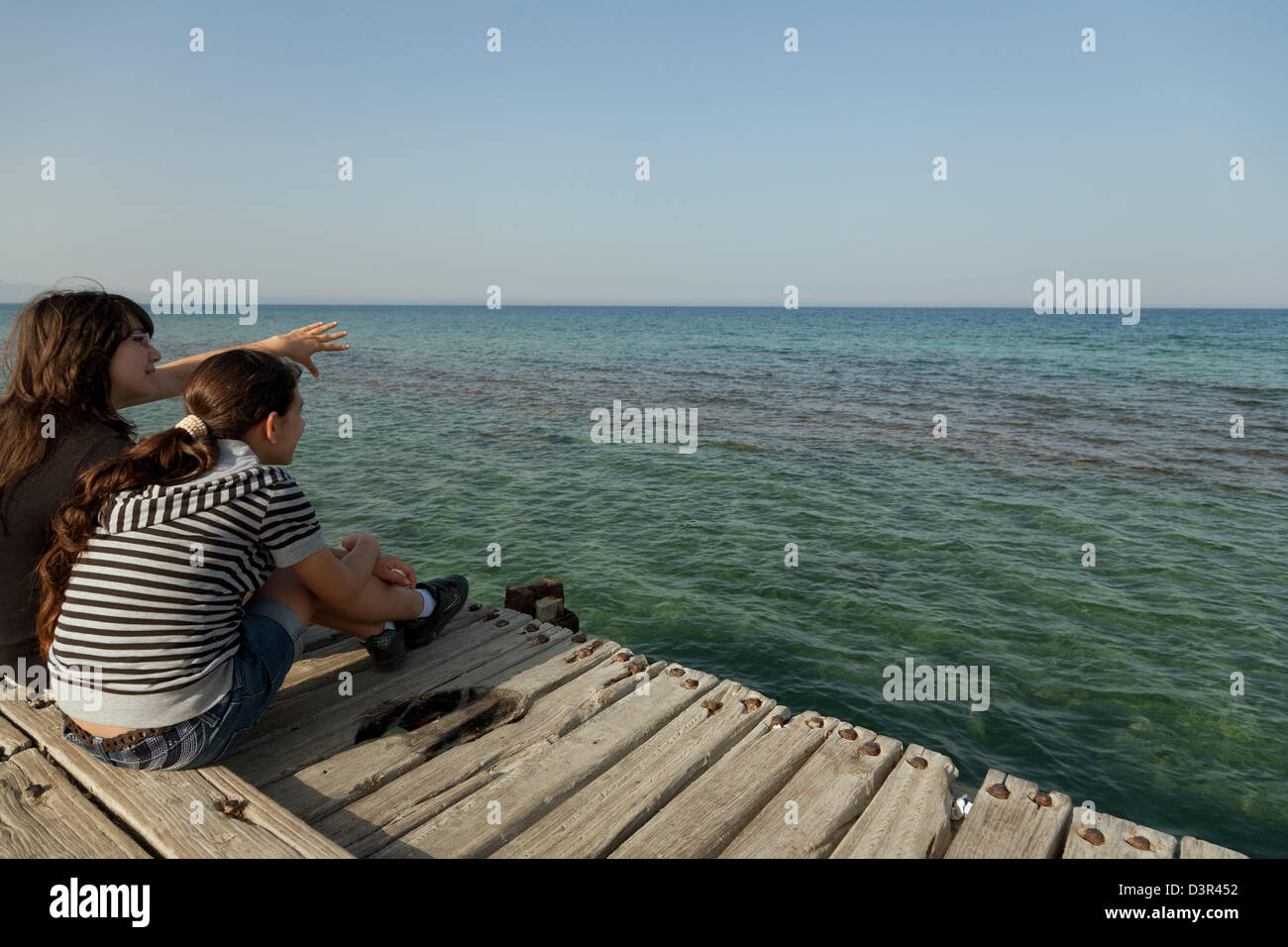 Famagusta, türkischen Republik Nordzypern, Mädchen sitzen auf einem Dock im Mittelmeer Stockfoto