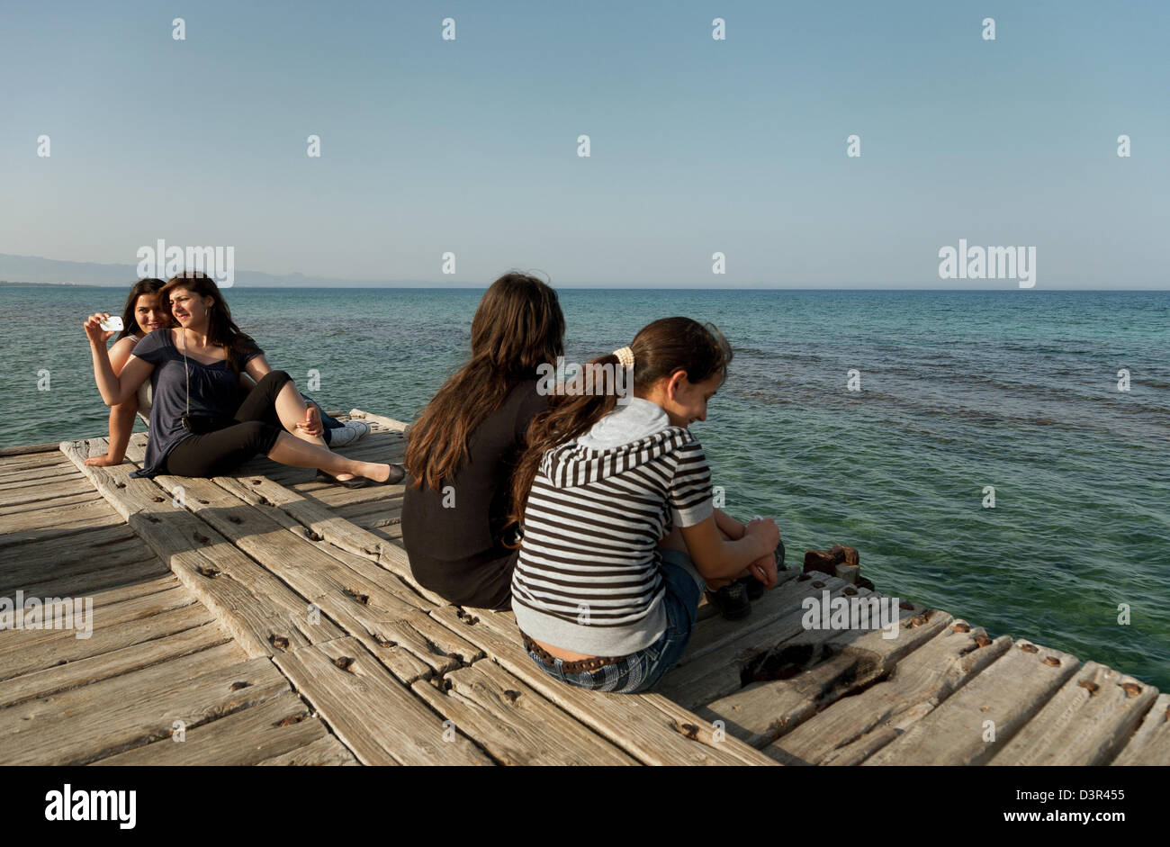 Famagusta, türkischen Republik Nordzypern, Mädchen sitzen auf einem Dock im Mittelmeer Stockfoto