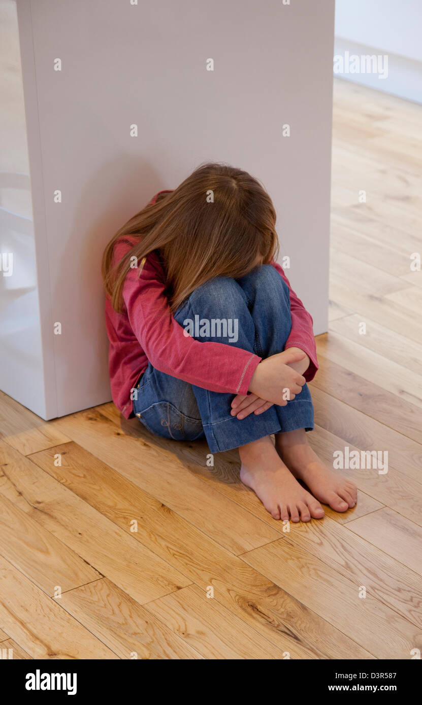 Junges Mädchen saß auf dem Boden unglücklich Stockfoto