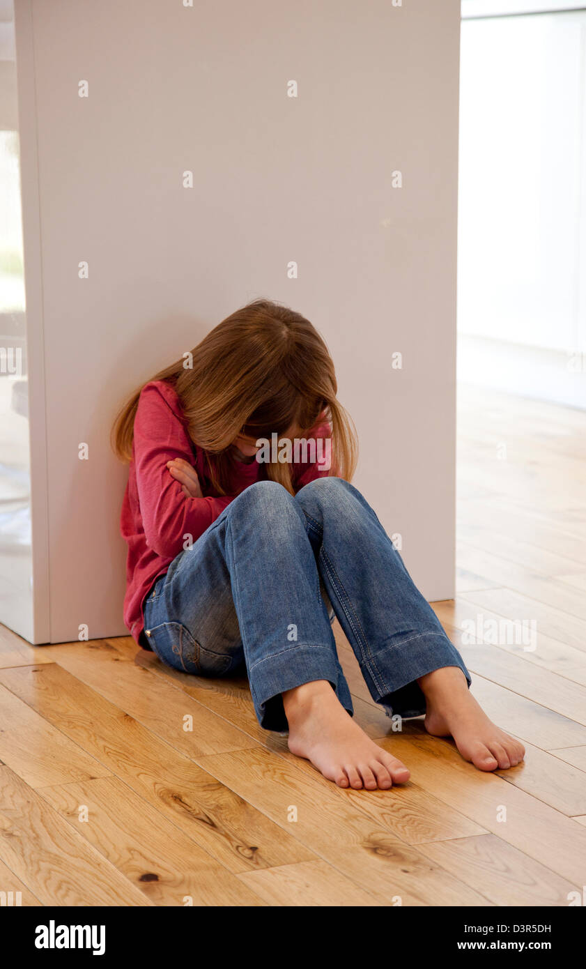 Junges Mädchen saß auf dem Boden unglücklich Stockfoto