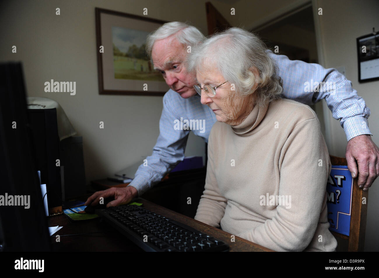 Mann, die Frau mit einem Computer zu Hause in seinem Büro zu helfen. Stockfoto