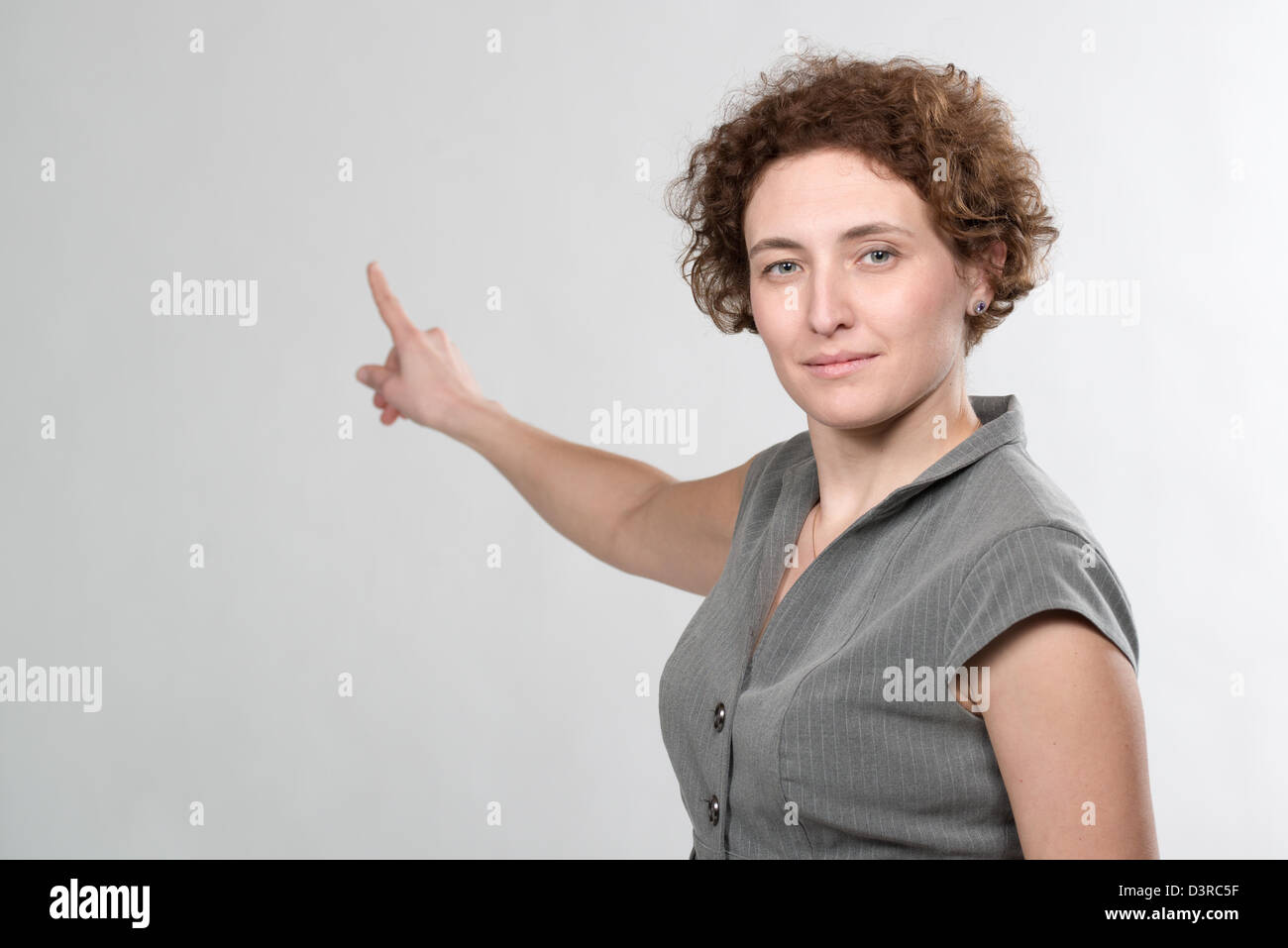 lockige Geschäftsfrau zeigt mit Finger auf weißem Hintergrund Stockfoto