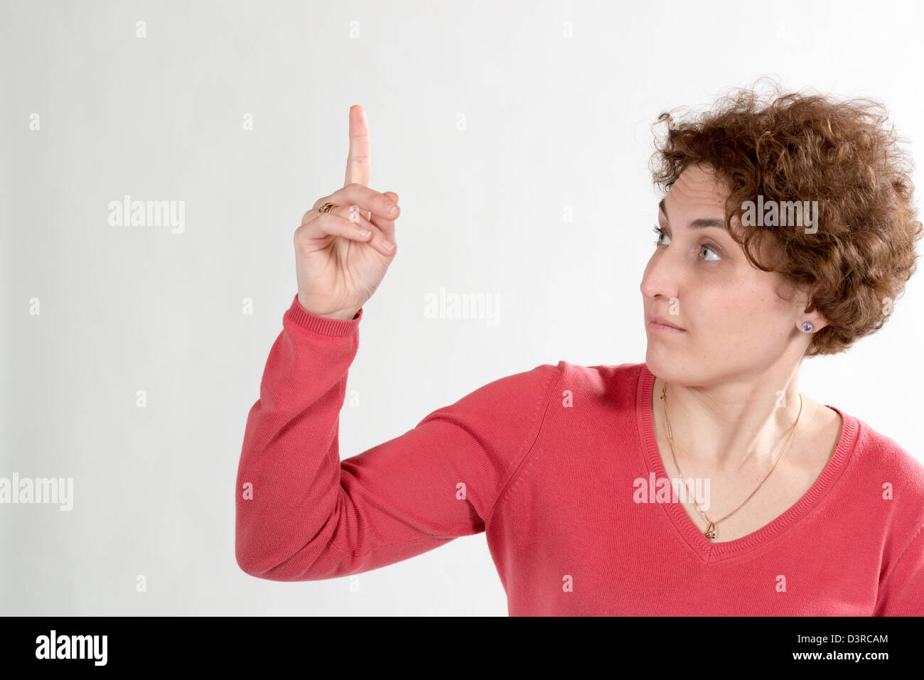 lockige Frau zeigen mit dem Finger und seltsam Aussehen verleihen Stockfoto