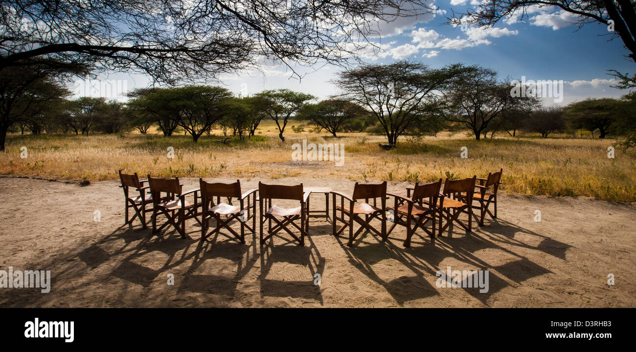 Eine Reihe von Stühlen eingerichtet, um den Sonnenuntergang über der Savanne zu sehen. Manyara Ranch Conservancy. Tansania Stockfoto
