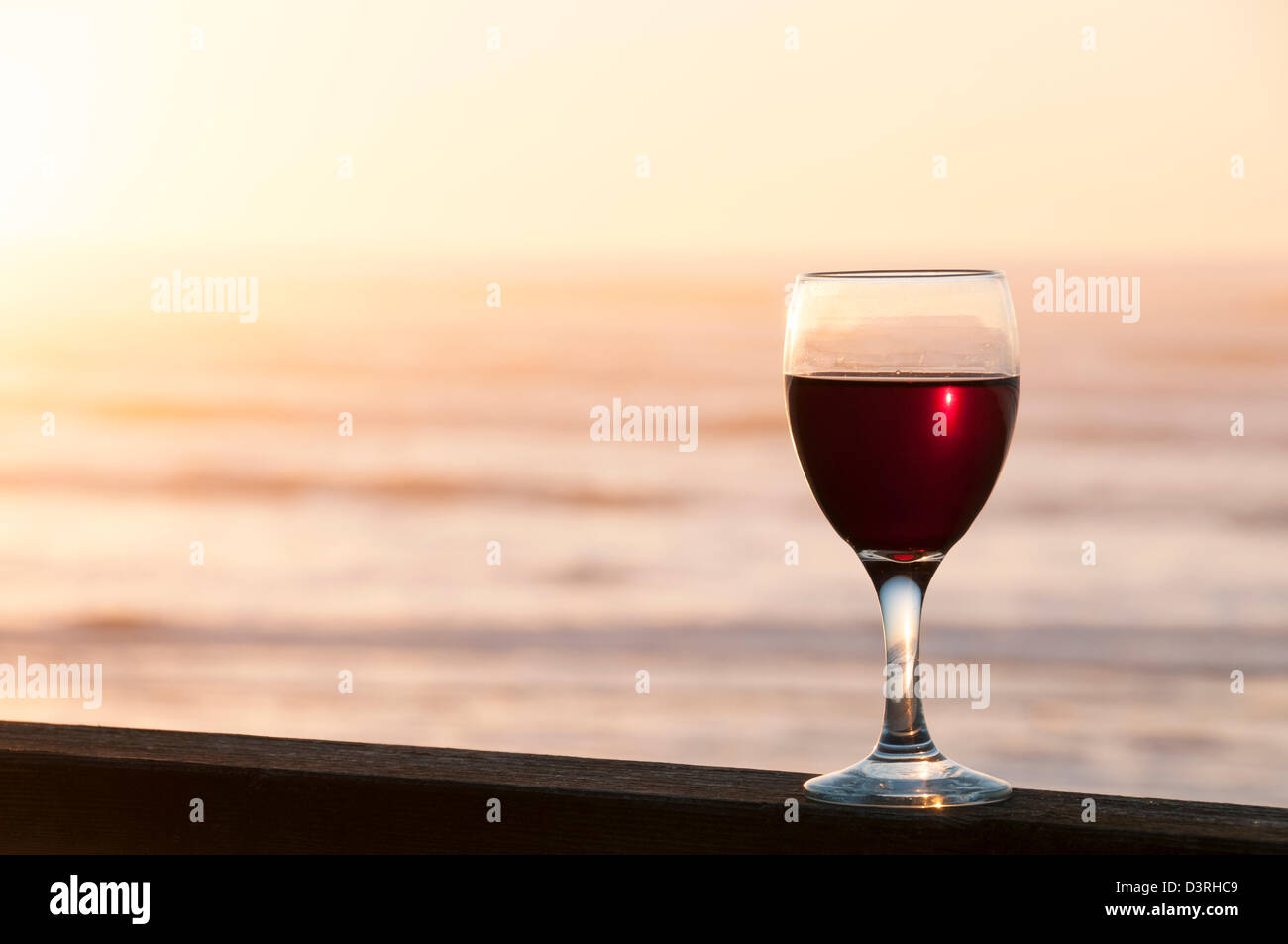Glas Rotwein auf Deck Geländer des Hauses am Strand im Ruhestand an der zentralen Küste Oregons. Stockfoto