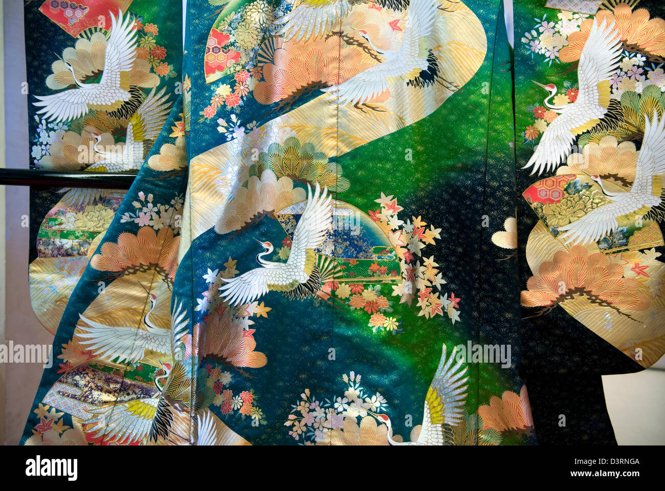 Frühling Hochzeit Kimono auf dem Display hat Darstellungen von Kirschblüten und japanische Kraniche vor einem farbigen Hintergrund. Stockfoto