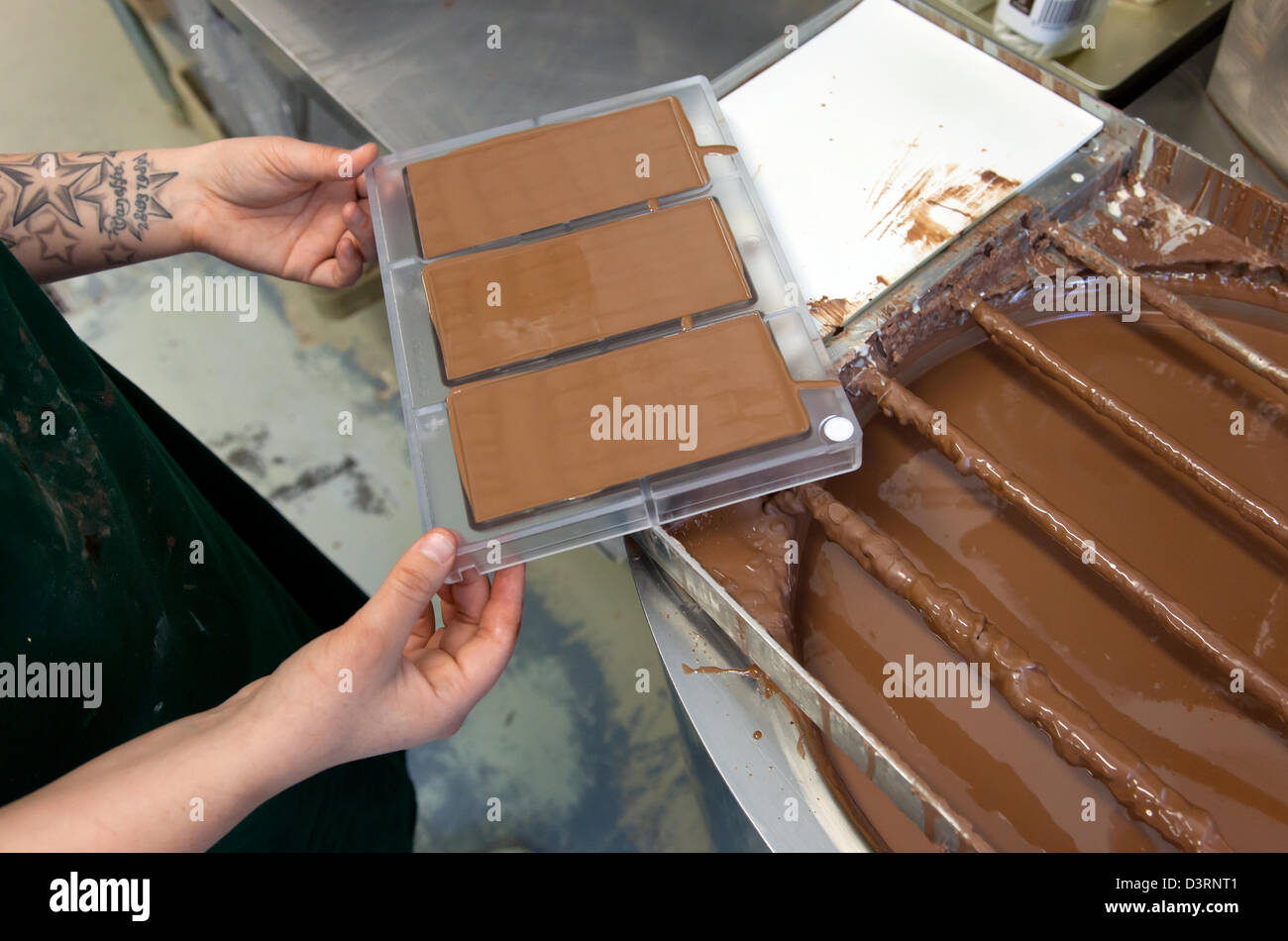 Berlin, Deutschland, Mitrabeiterin von Chocri füllt eine Schokolade Orte in Formen Stockfoto