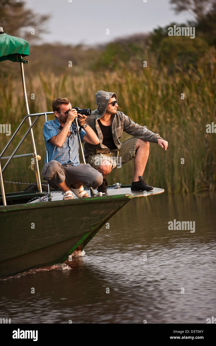 Fotografen, die Bilder von einem Boot in Phinda Game Reserve, Südafrika Stockfoto