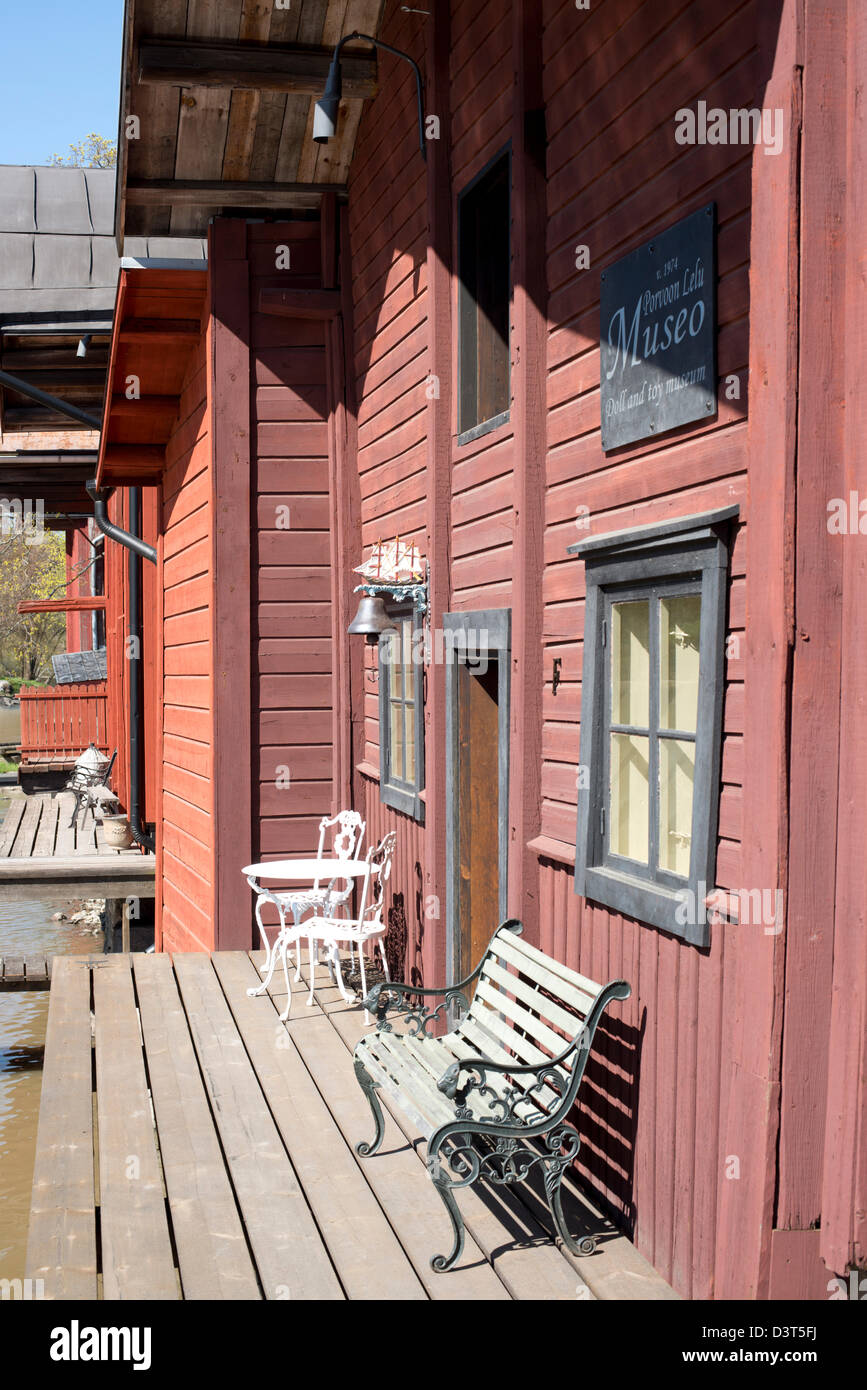 Bank, Stühle und einen kleinen Tisch auf der Terrasse am Wasser vor einem traditionellen roten Holzhaus in Porvoo, Finnland Stockfoto