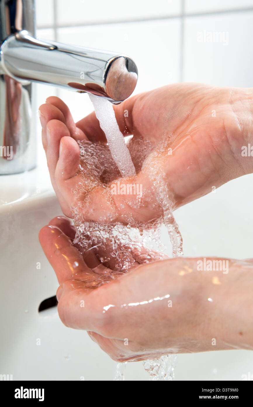 Person wäscht ihre Hände unter fließendem Wasser aus einem Wasserhahn im Badezimmer. Symbol-Bild für Wasserverschwendung. Stockfoto