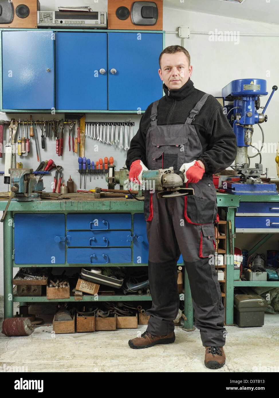 Schlosser halten eckige Schleifer beim Posieren in seiner Werkstatt Stockfoto