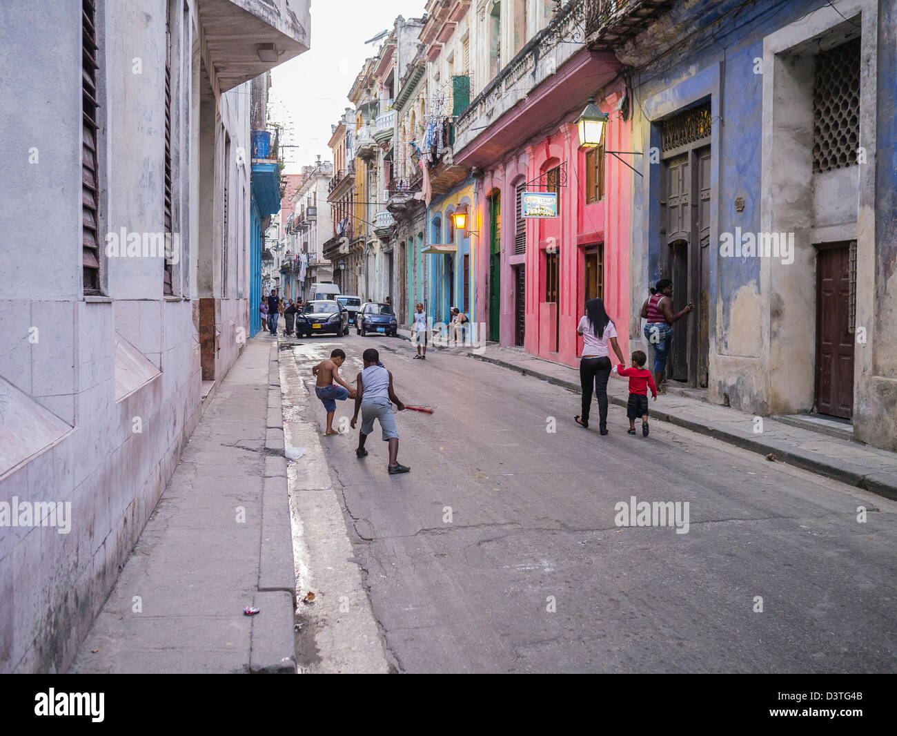 Kinder spielen Baseball in der Straße in Havanna, Kuba mit bunten alten kolonialen Gebäude entlang der schmalen Straße. Stockfoto