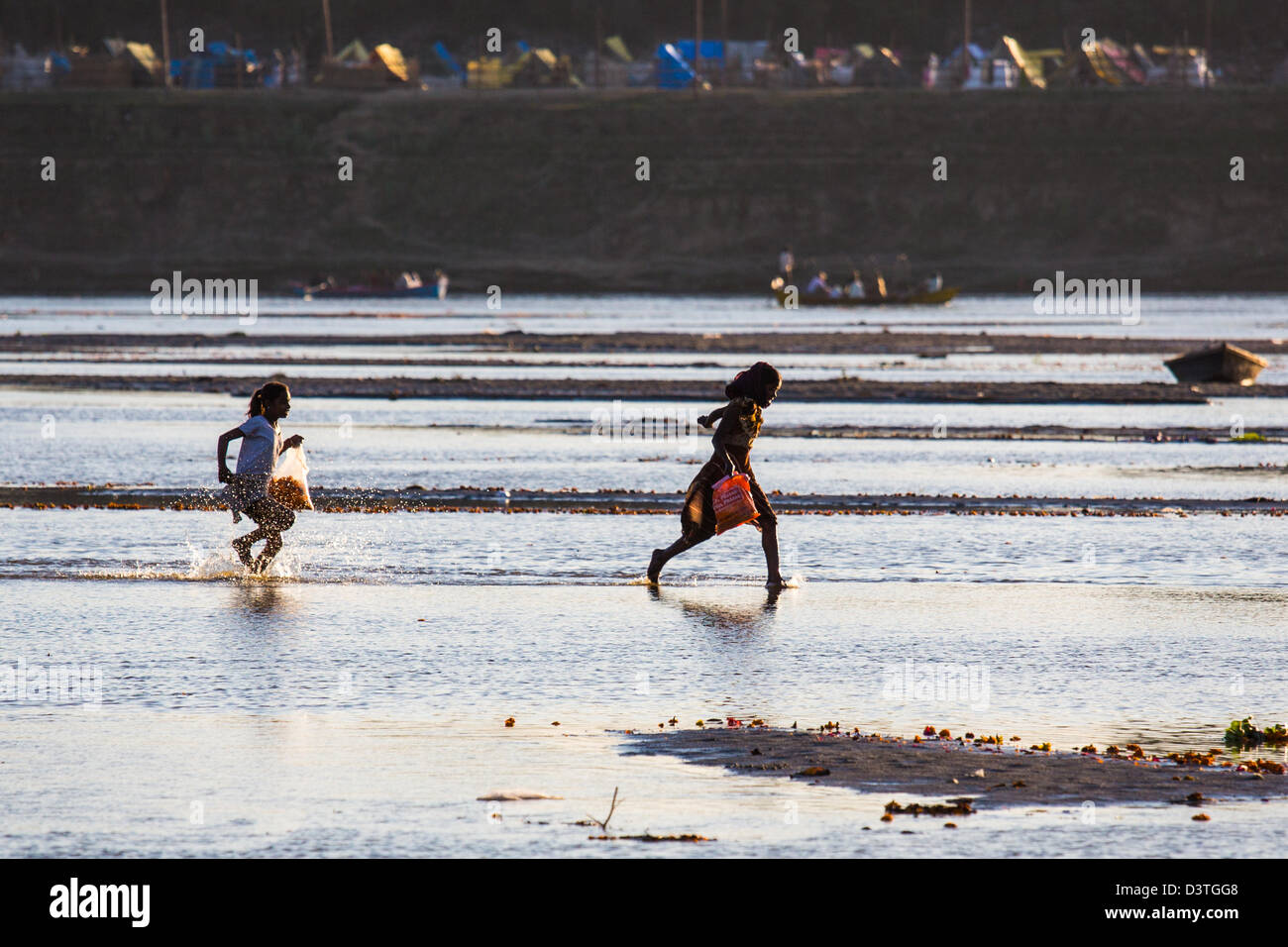 Mädchen sammeln Blumen aus dem Fluss auf der Kumbh Mela, Allahabad, Indien Stockfoto