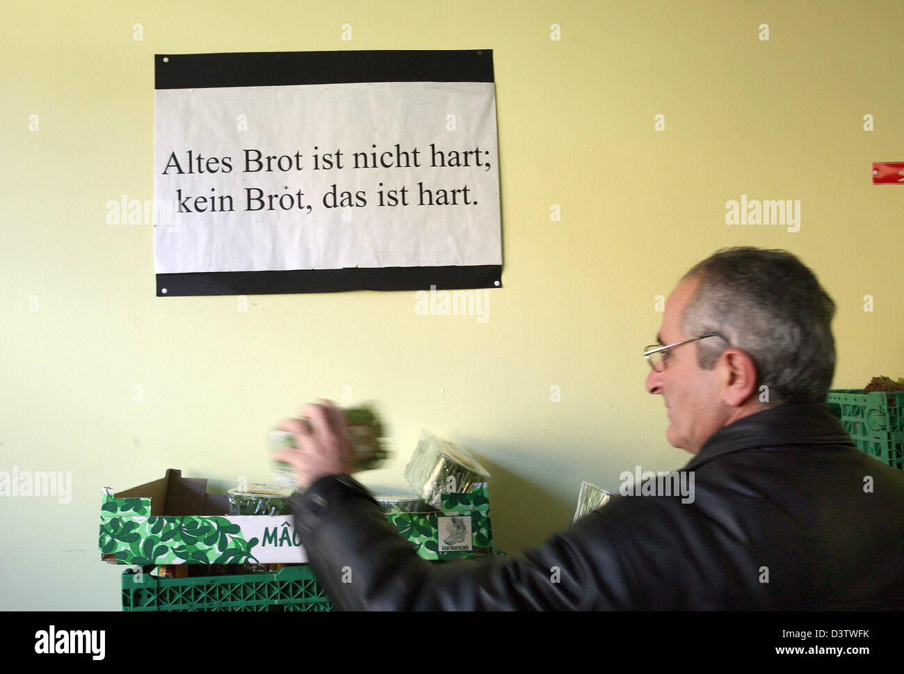 Ein Mann nimmt Brot aus einer Box unter dem Zeichen mit der Meldung "Altes Brot ist Nicht Hart; Kein Brot, Das ist Hart "(lit.:"altes Brot ist nicht schwer zu ertragen; kein Brot ist schwer zu ertragen") bei der Stiftung"Kasseler Tafel e.V."in Kassel, Deutschland, Mittwoch, 15. November 2006. Die "Kasseler Tafel" Stiftung mit mehr als 70 ehrenamtlichen Mitarbeitern bietet Nahrung für mehr als 1.000 famil Stockfoto