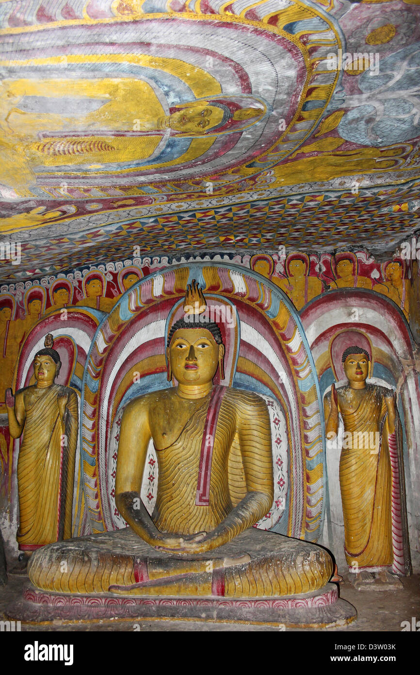 Sitzende Buddha-Statuen und bemalte Decke im Inneren des Maha Alut Viharaya Cave Tempels Stockfoto