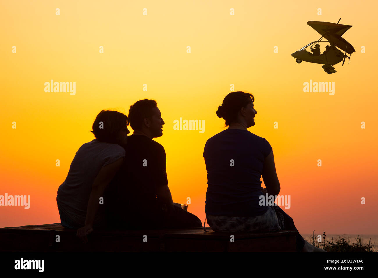 Menschen entspannen am Meer in einer Ferienanlage in Myrina Lemnos, Griechenland bei Sonnenuntergang mit einem motorisierten Hängegleiter Stockfoto