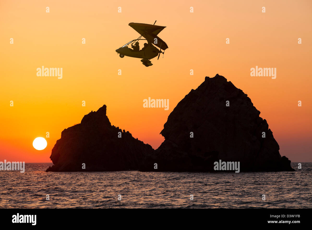 Sonnenuntergang über felsigen Inseln vor Myrina auf Lemnos, Griechenland, mit einem motorisierten Gleitschirm. Stockfoto