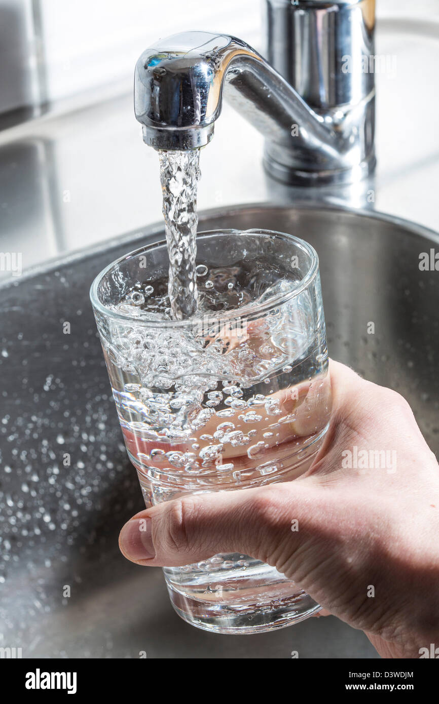 Wasser läuft in einem Glas, aus einem Wasserhahn in der Küche  Stockfotografie - Alamy