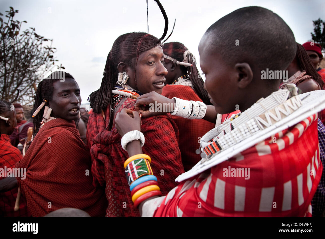 Eine junge Massai Frau behebt eine junge Moran Kleidung, nachdem sie gekommen sind, von zu viel tanzen zu verlieren. Stockfoto
