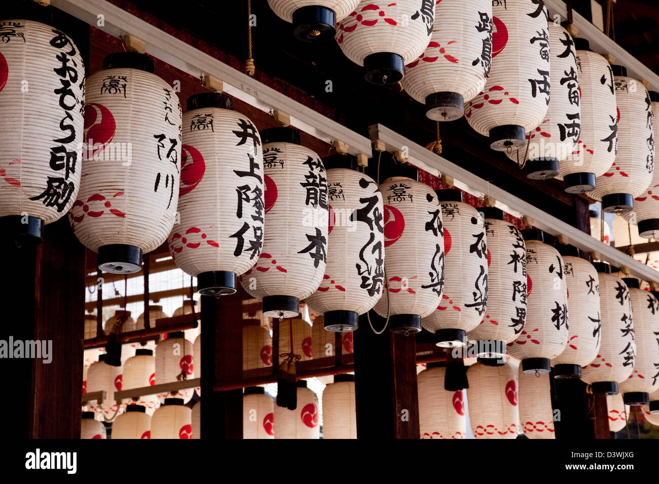 Traditionelle japanische Papierlaternen oder Chochin in einem Kyoto-Schrein jetzt oft beleuchtet von Elektrizität und die Steckdosen sind sichtbar. Stockfoto