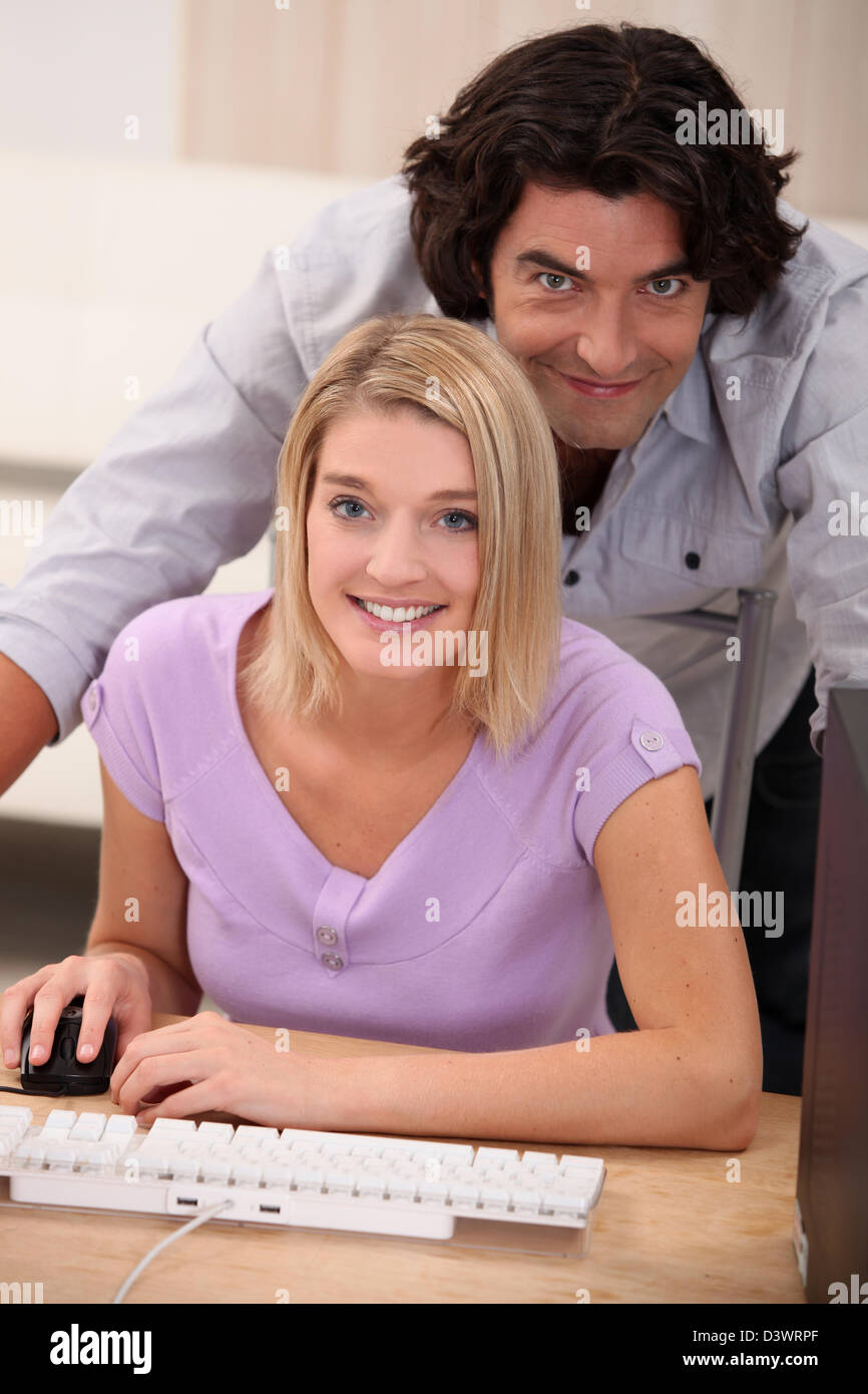 eine blonde Frau, die Computer und ihr Ehemann vor der Kamera zu tun Stockfoto