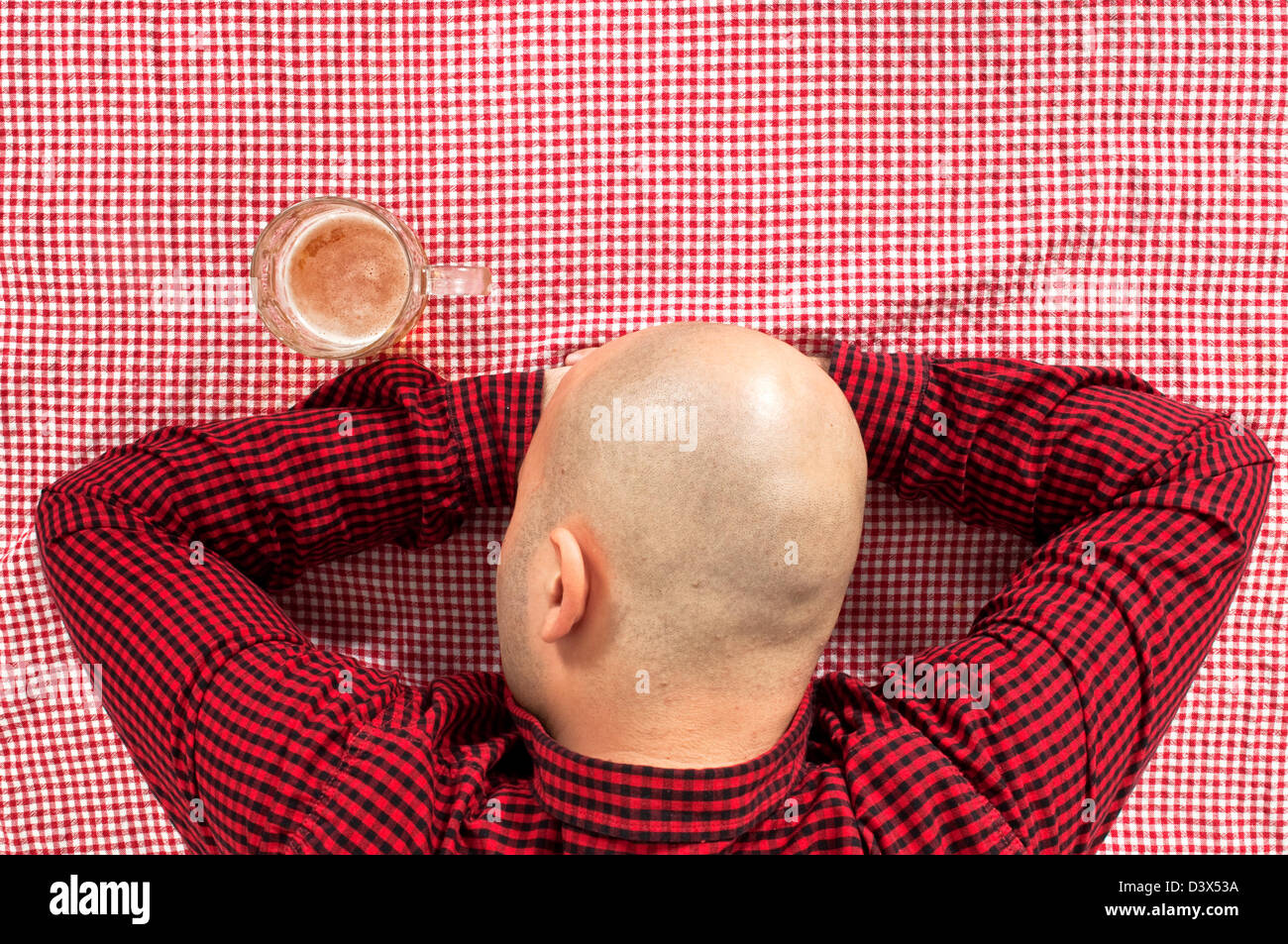 Glatze Biertrinker in der Bar bei einem Glas kaltes Bier auf dem Tisch sitzen. Stockfoto