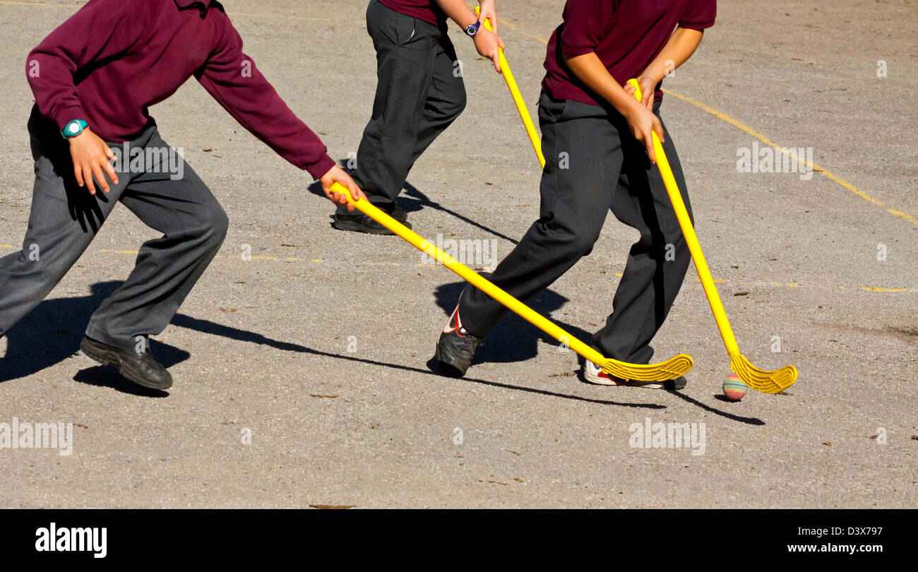 Detail der Kinder im Grundschulalter spielt Hockey auf einem Schulhof Stockfoto