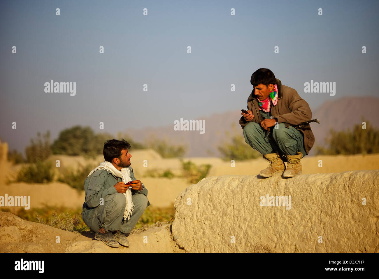 Zwei afghanische Polizisten haben ein Gespräch während ihrer Frühschicht im Dienst an einer Straßenseite. Stockfoto