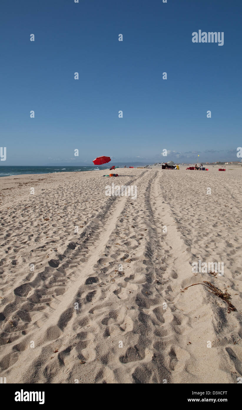 Reifenspuren, in den weißen Sand des Strandes in Costa Verde, Portugal, kontrastiert gegen Aclear blau, und der Schirm, s Stockfoto