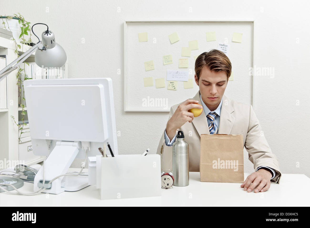 Ein Konzept-Foto von eine junge Büroangestellte versucht, Geld zu sparen, indem man Mittagessen zu arbeiten. Stockfoto