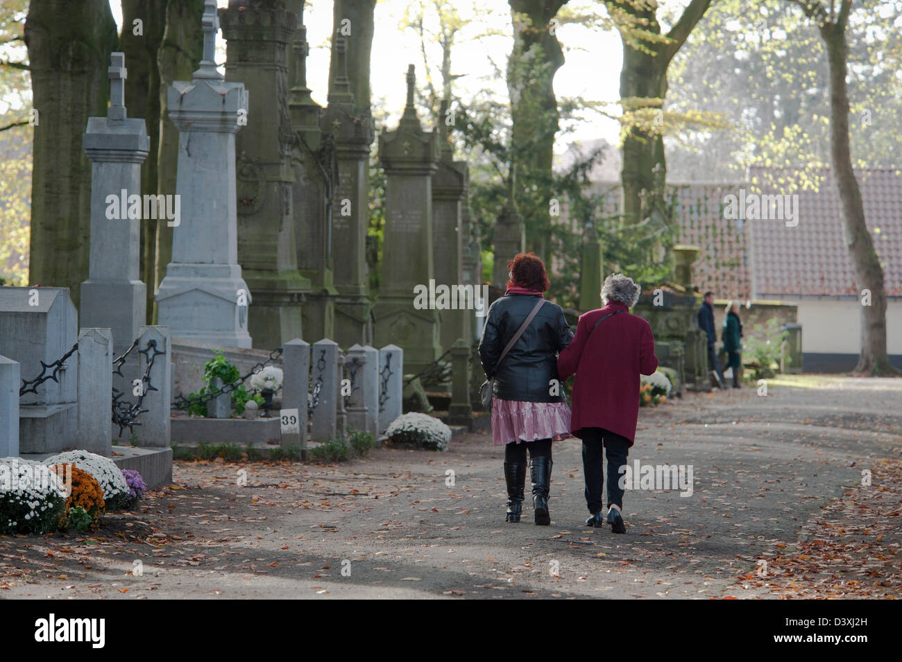 Zwei Damen gehen durch den Friedhof die Gräber ihrer Angehörigen für Allerheiligen vorzubereiten. Stockfoto