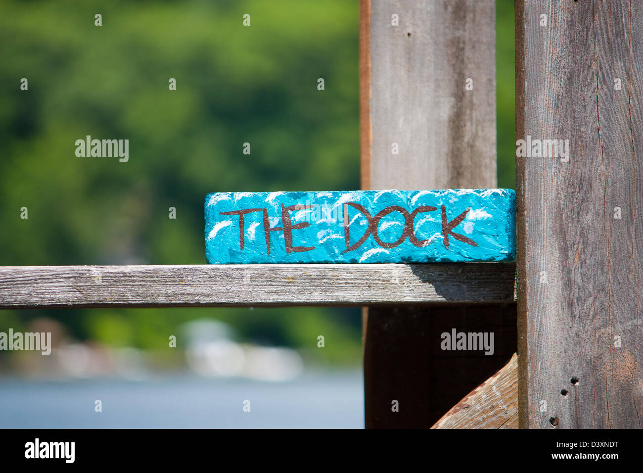 Fokus auf der Anklagebank flach und dock-Zeichen. Den Sommer See und die Bäume sind im Hintergrund unscharf. Stockfoto