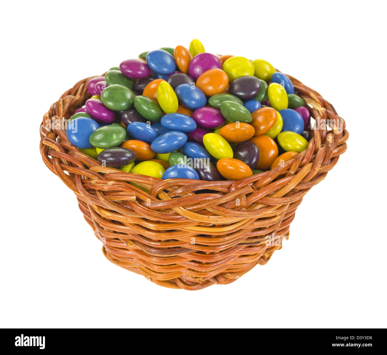 Ein kleiner Korb gefüllt mit bunt gestrichenen Schokoladenstücke. Stockfoto