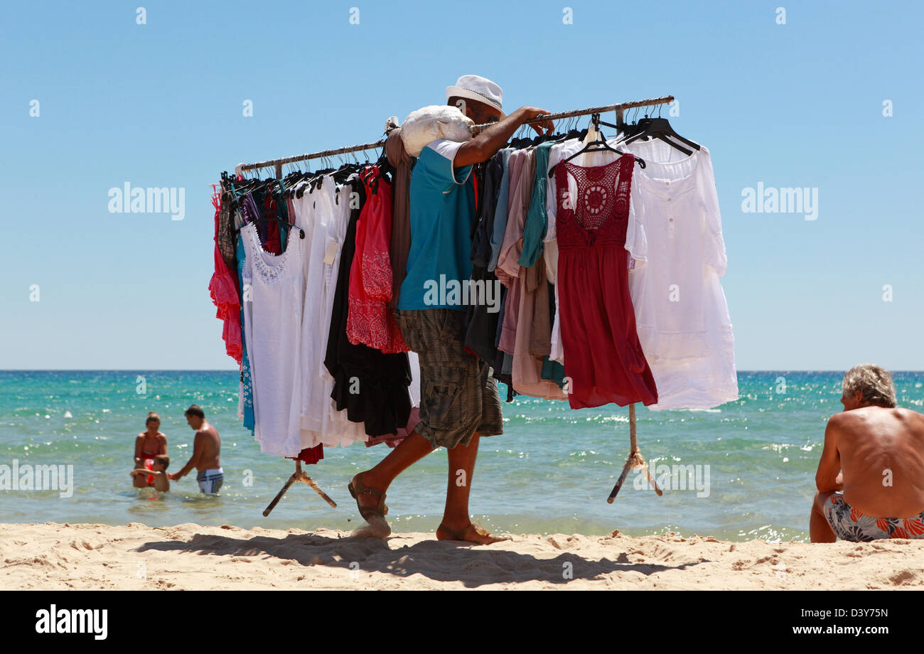 Santa Margherita di Pula, Italien, Mann trägt eine Kleiderstange mit T-shirts am Strand entlang Stockfoto