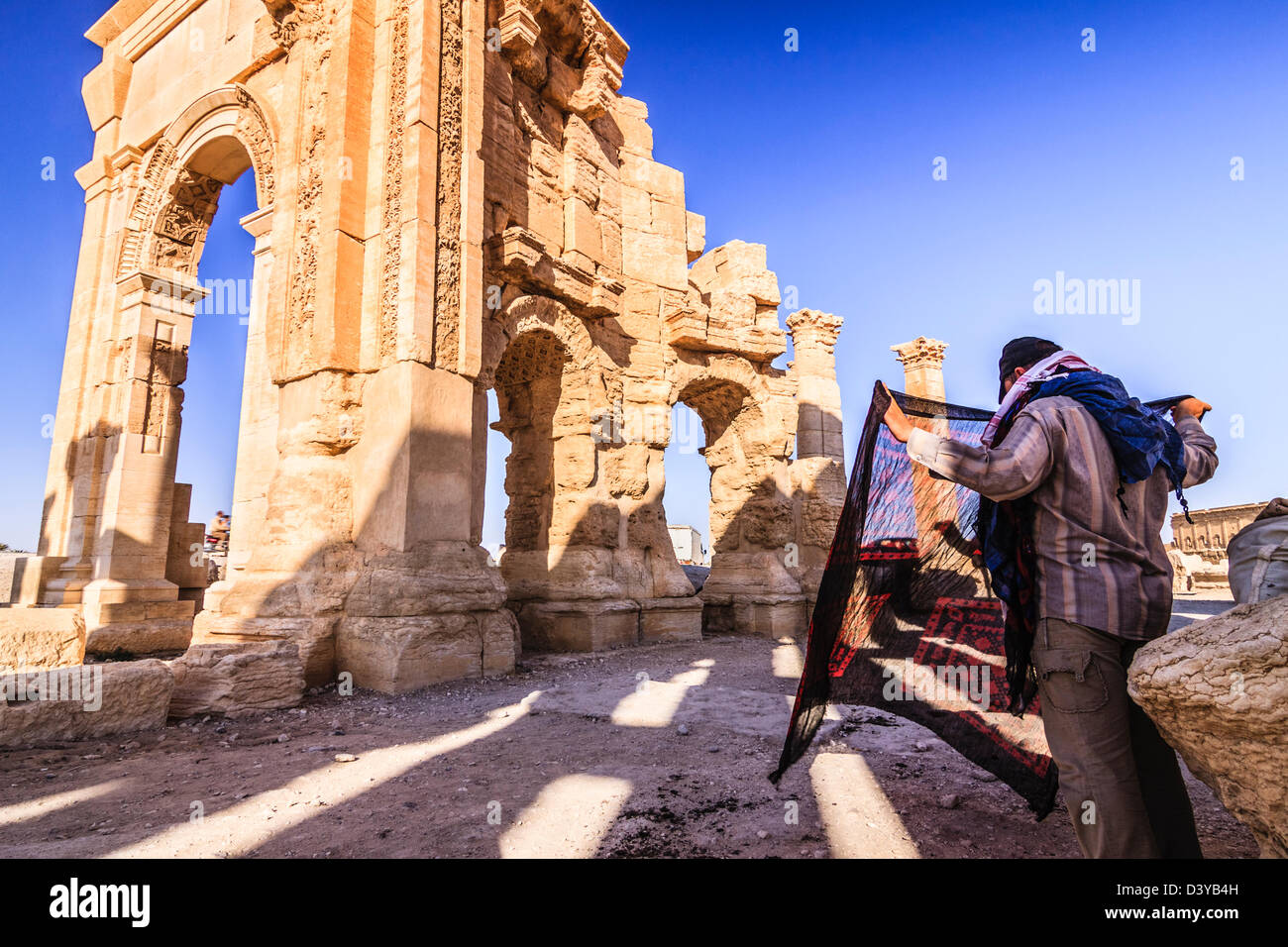 Seide Souvenirs Verkäufer warten auf Touristen in den Ruinen der monumentalen Bogen von Palmyra. Palmyra, Syrien Stockfoto