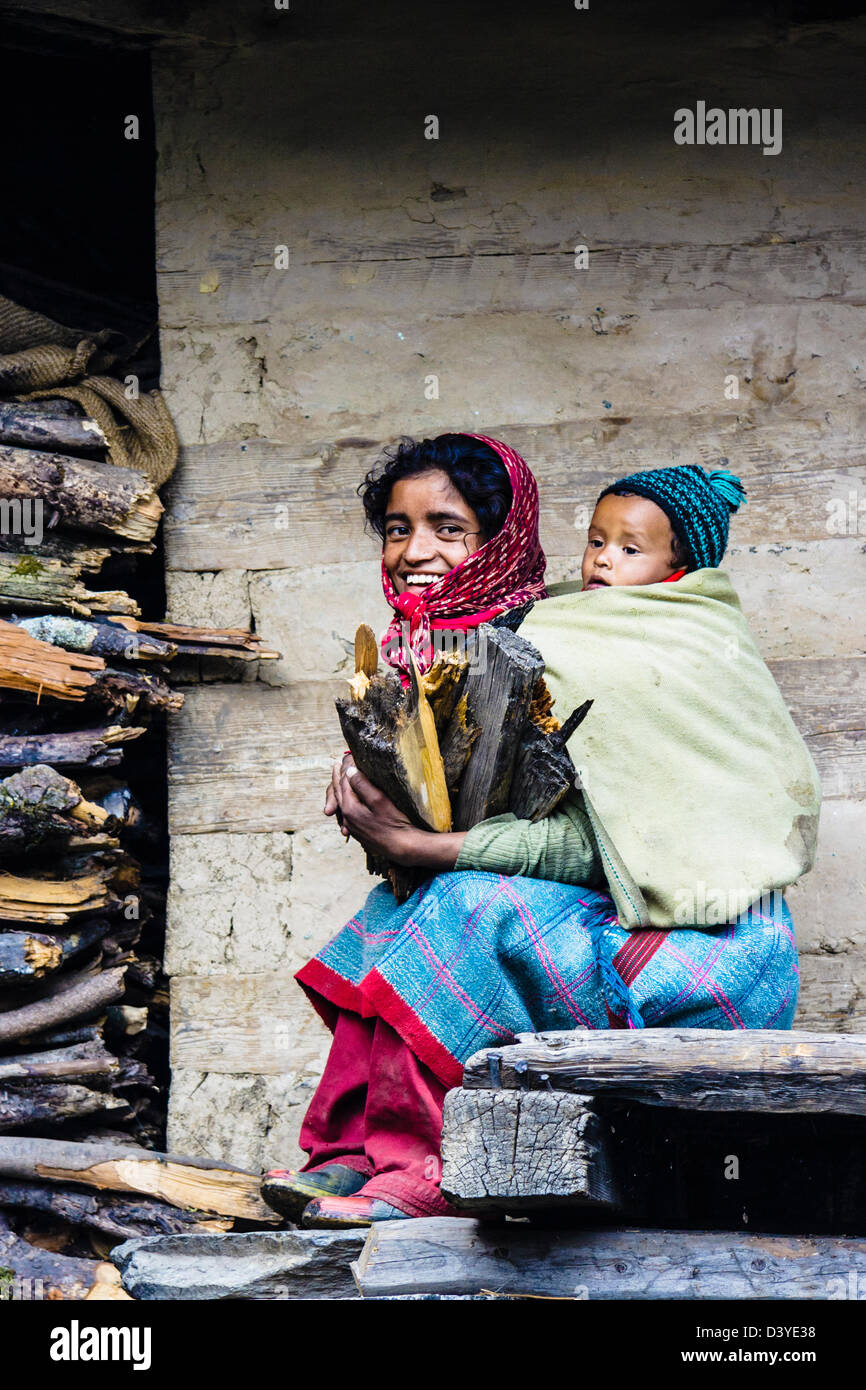 Junges Mädchen sammeln von Holz mit Baby auf dem Rücken. Malana Dorf, Himachal Pradesh, Indien Stockfoto