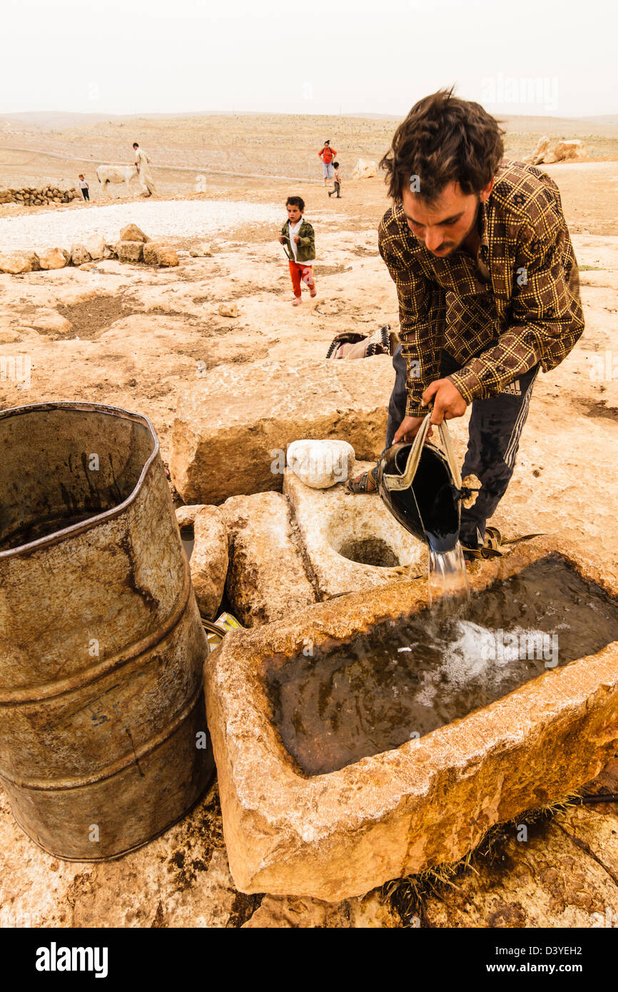 Ein Hirte füllt mit Wasser eine Tränke auf die Ruinen von Mushabbak ein altes Taufbecken umgewandelt. Syrien Stockfoto