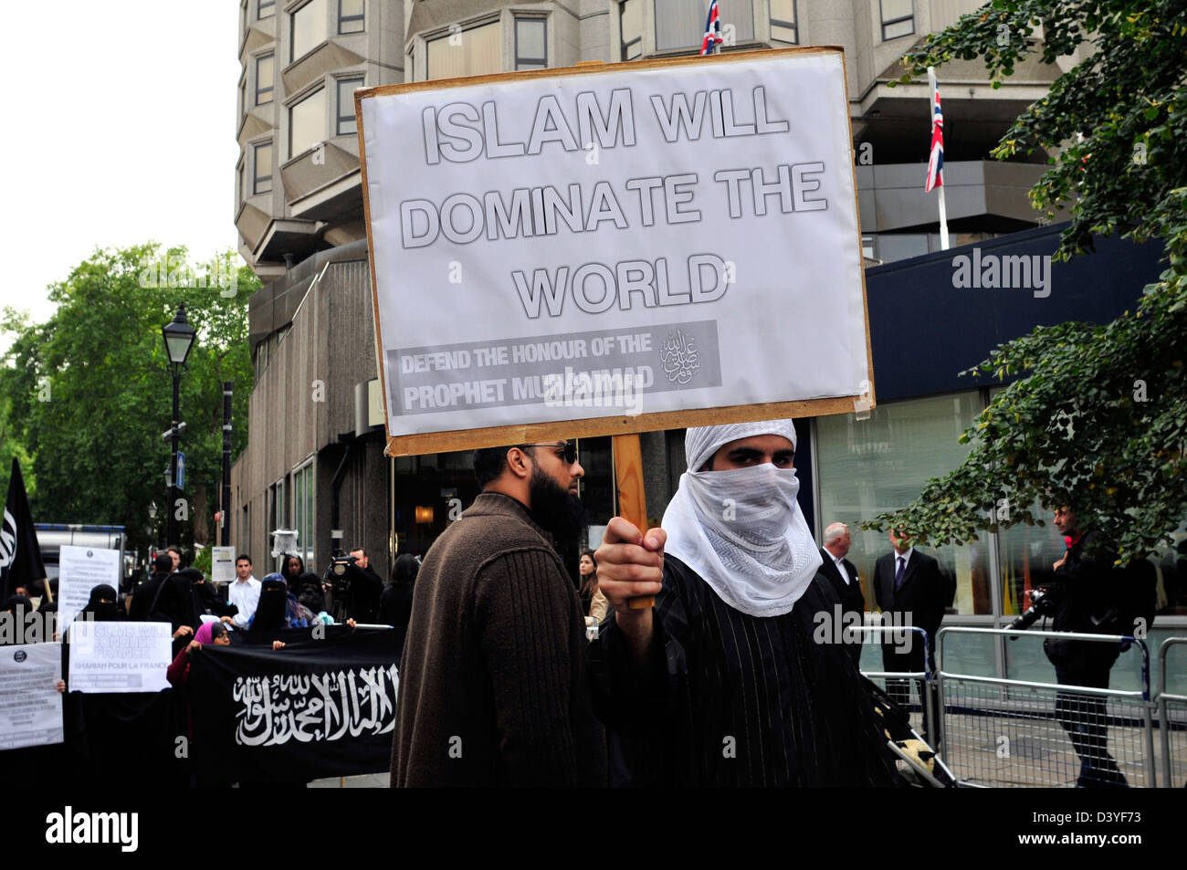 Ein Demonstrant mit seinem Gesicht bedeckt hält ein Plakat lesen "Islam wird die Welt beherrschen" Stockfoto