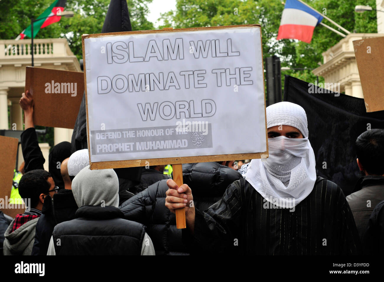 Eine islamistische Demonstrant mit seinem Gesicht bedeckt, hält ein Plakat lesen "Islam wird die Welt beherrschen" Stockfoto