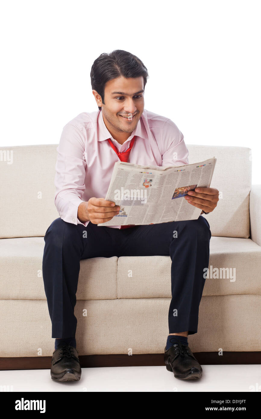Geschäftsmann auf einer Couch sitzen und eine Zeitung lesen Stockfoto