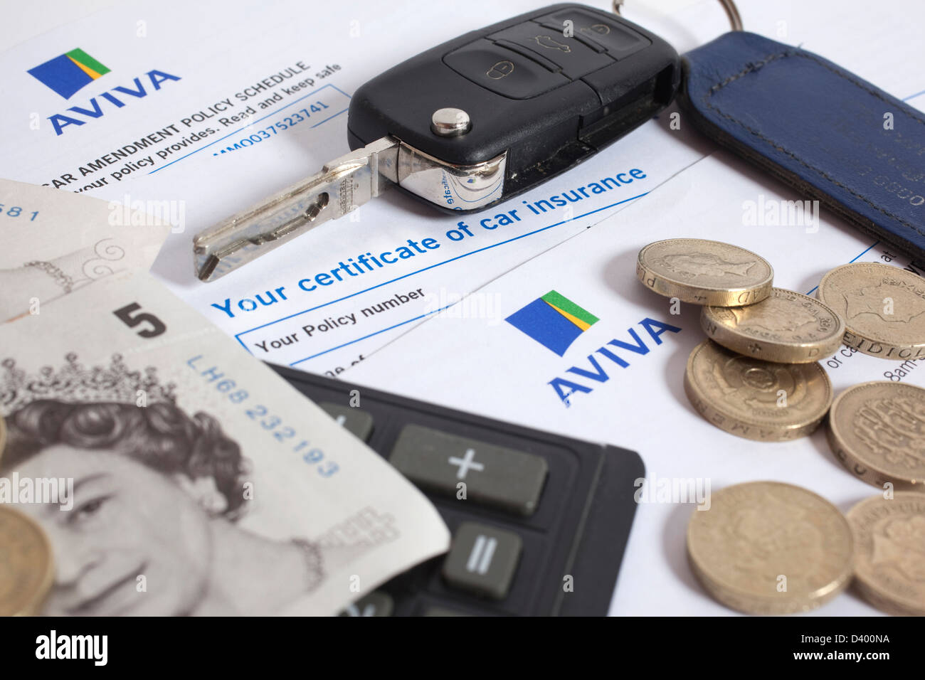 Motor Versicherungsschein neben Geld, Schlüssel und Rechner Stockfoto