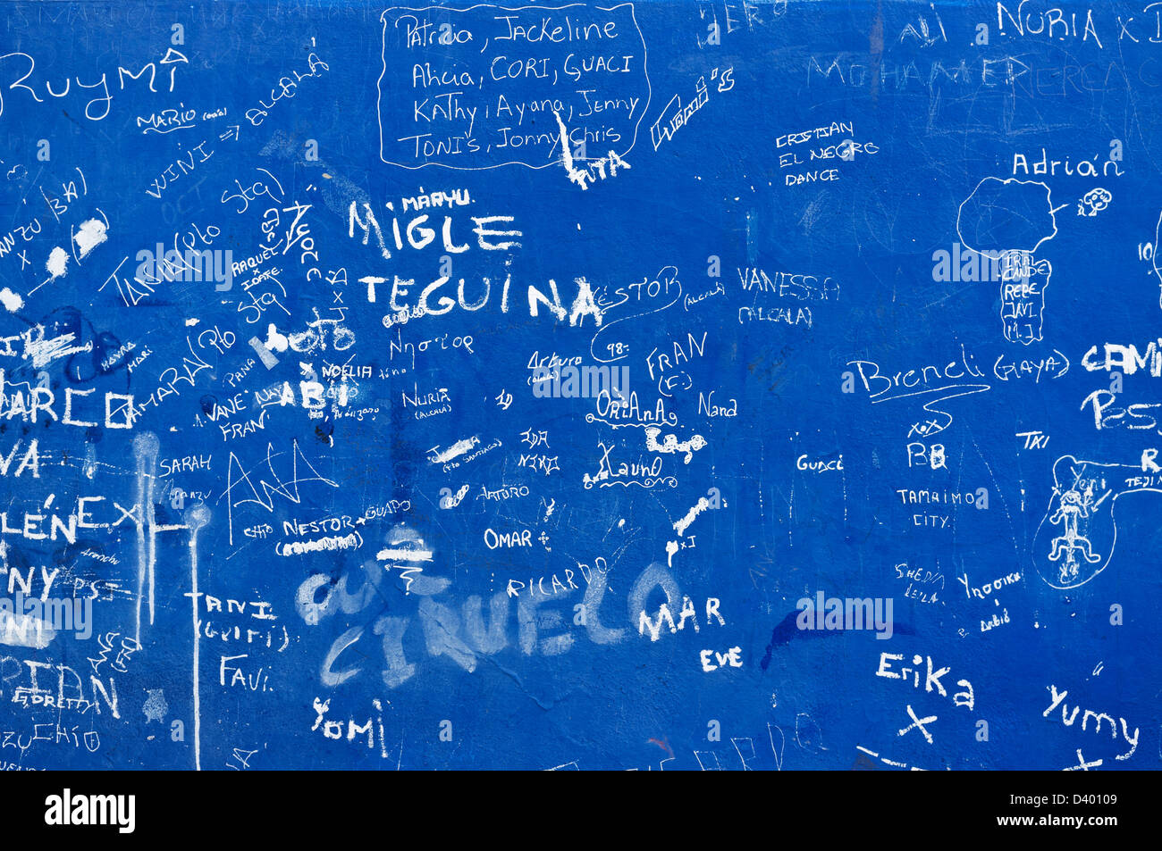 Blaue Graffitiwand mit spanischen Namen in Lack zerkratzt Stockfoto