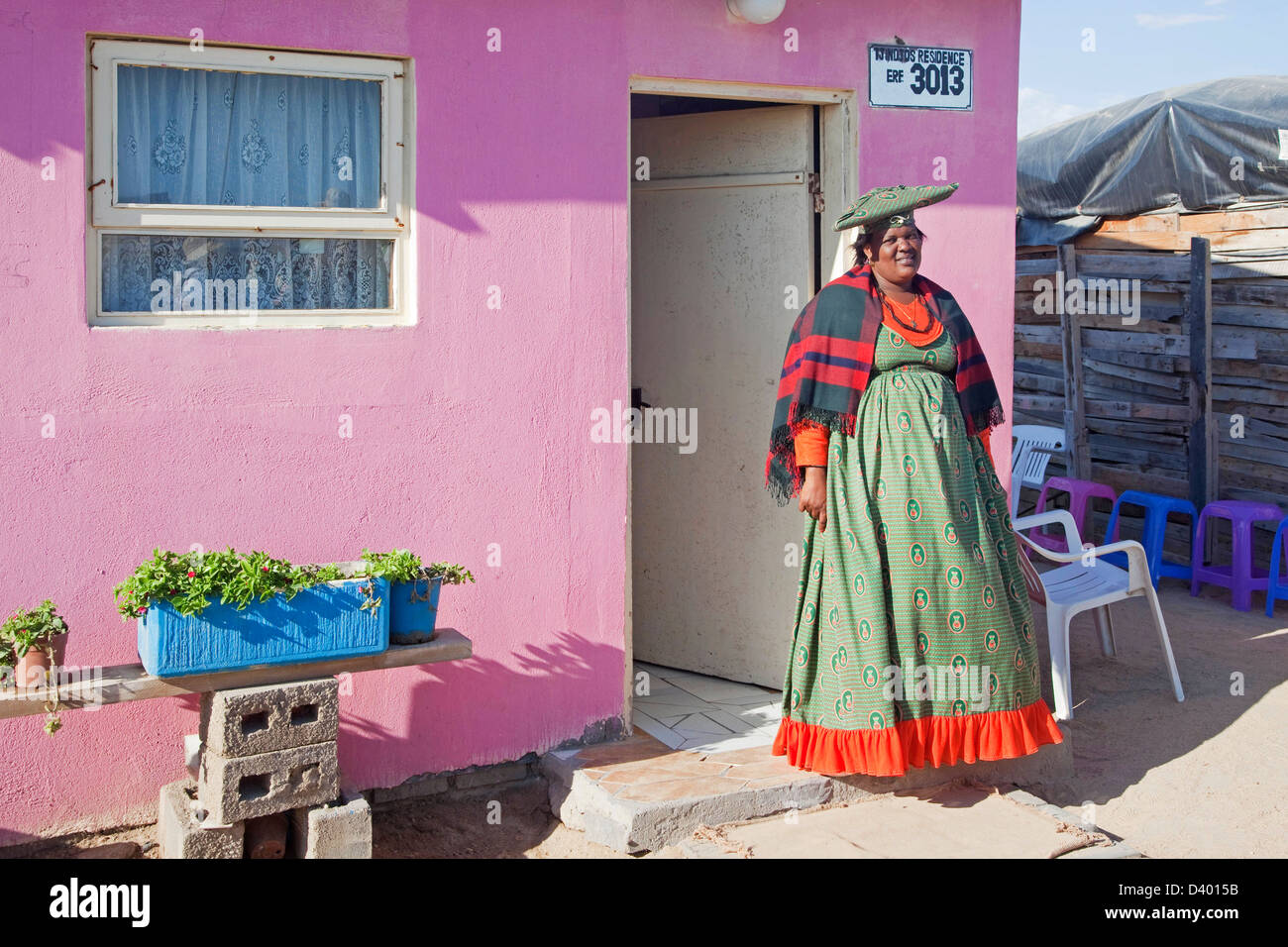 Herero-Frau in bunten Trachten vor ihrem Haus in der Gemeinde in der Nähe von Swakopmund, Namibia, Südafrika Stockfoto